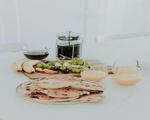 A balanced breakfast table setup with whole fresh fruits and a relaxing infusion glass