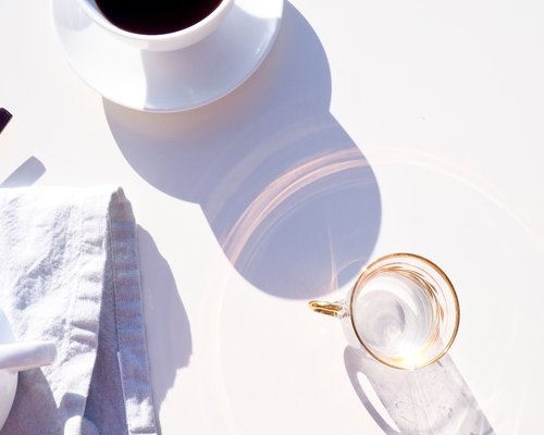 A detailed top view of a fresh glass of water placed purposefully next to an elegant porcelain coffee cup